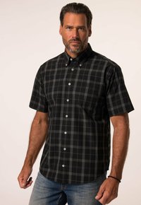 Camicia a maniche corte con bottoni in un motivo a quadri nero e grigio, con bottoni bianchi e una tasca sul petto. Il materiale sembra leggero e texturizzato.