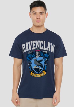Young man wearing a navy blue T-shirt with a large Ravenclaw crest and the word "RAVENCLAW" printed above and below the design.