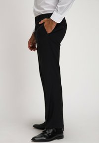 Pantaloni neri su misura con vestibilità slim, senza pieghe sul davanti, tasche laterali e una trama liscia, indossati con scarpe eleganti nere.