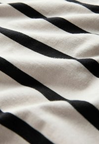 Mustekki ja valkoiset raidat, joissa on pehmeä, tekstuurinen pinta, näyttäen taitoksia ja ryppyjä, jotka korostavat vastakkaista värikuviota.