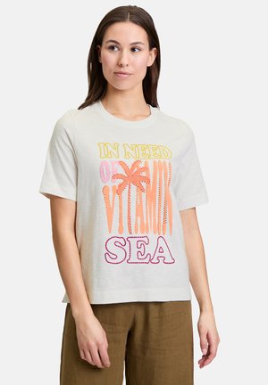 T-shirt gris clair à manches courtes avec un texte coloré : "EN BESOINS DE VITAMINE MER" et un design de palmier. Coupe décontractée avec encolure ronde.