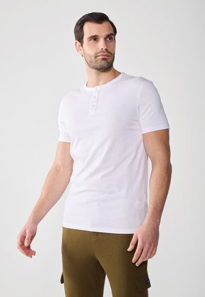 Bílý krátký rukáv henley tričko s kruhovým výstřihem, s třemi knoflíky na límci, vyrobené z bavlněné látky, hladká textura.