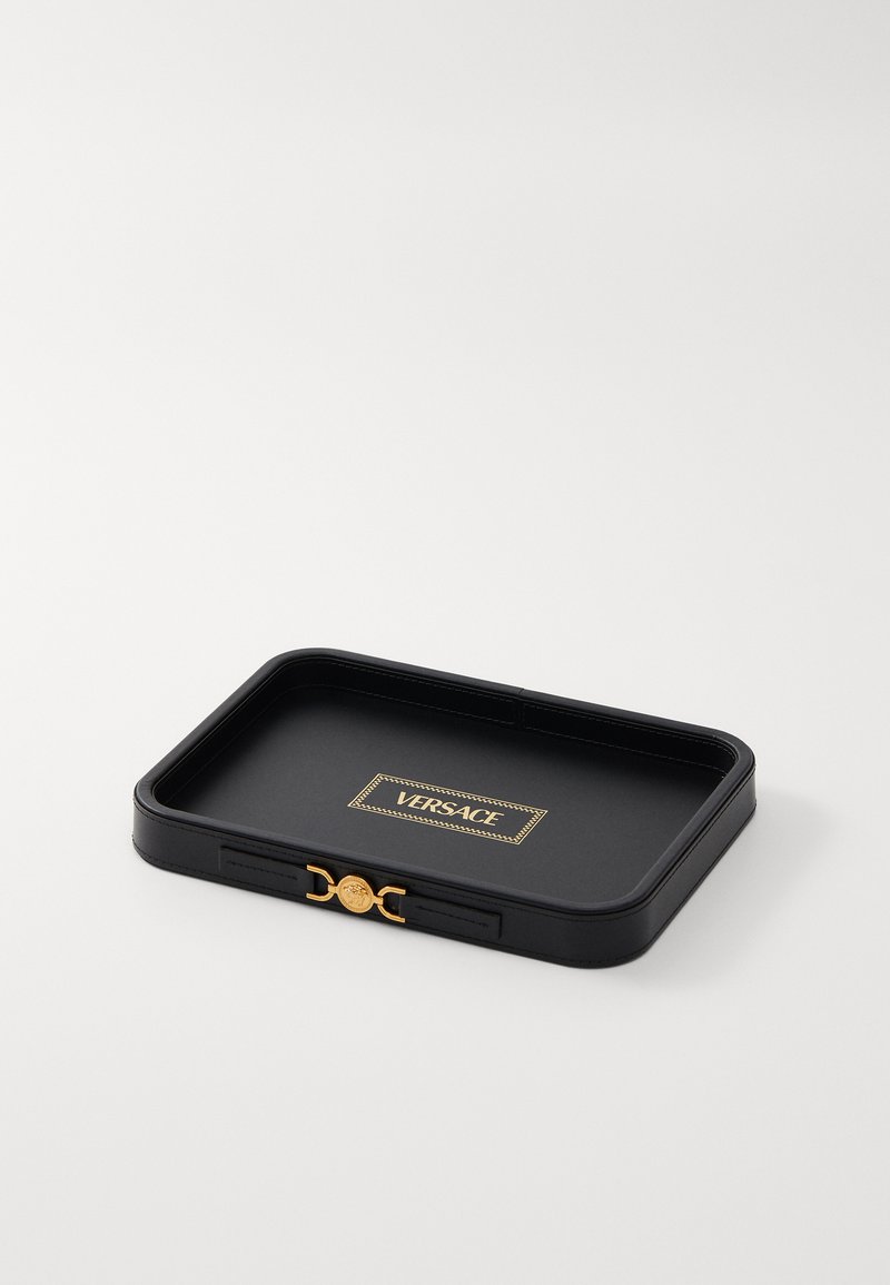 Bandeja rectangular negra con acentos dorados y un logo de Versace. Presenta una textura suave y bordes ligeramente elevados para mayor estabilidad.