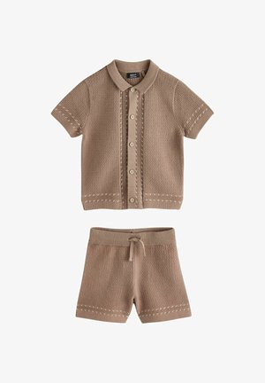 Dviejų dalių megztas kostiumas šviesiai rudos spalvos, sudarytas iš trumpomis rankovėmis megztos su sagomis palaidinės su raštu ir derančių šortų su raišteliu liemenėje.