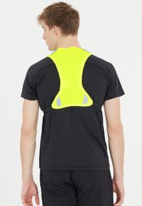 Schwarz athletic Shirt mit einer reflektierenden neon-gelben Weste, die ein hochsichtbares Design und verstellbare Riemen auf der Rückseite aufweist.