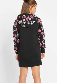 Abito felpa nero con maniche e cappuccio a fantasia floreale. Realizzato in tessuto morbido, presenta polsini a costine e una vestibilità comoda.