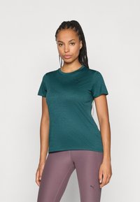 Teal kortermet treningst-skjorte i et jevnt stoff med rund hals og subtil logo på brystet, kombinert med lilla leggings.