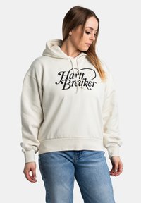 Crème hoodie met zwarte tekst "Heart Breaker," geribbelde manchetten en een kangoeroe zak; zachte stof en een relaxte pasvorm.