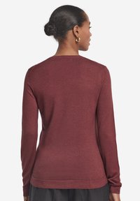 Maglione bordeaux a maniche lunghe con scollo rotondo, tessuto morbido e bordo a coste. Design semplice senza motivi visibili o dettagli hardware.