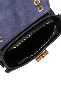 Zwarte leren handtas met een paarse suède klep. Voorzien van gouden hardware, een bamboe sluiting en een ritsvak aan de binnenkant.