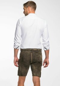 Bruna mockaskorts med en slim fit, med ett bälte, sömnadsdetaljer och sidofickor, kombinerade med en vit skjorta med knappar.