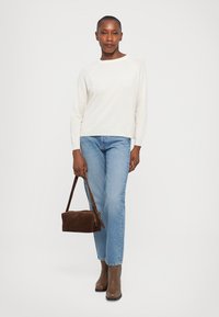 White ribbed sweater, light blue denim jeans, brown suede handbag, and brown ankle boots with a slight heel. Simple and casual outfit.