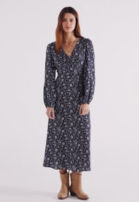 Marineblaues Maxikleid mit langen Puffärmeln, V-Ausschnitt und tailliertem Schnitt, aus leichtem Stoff mit dezenten Druckdetails.
