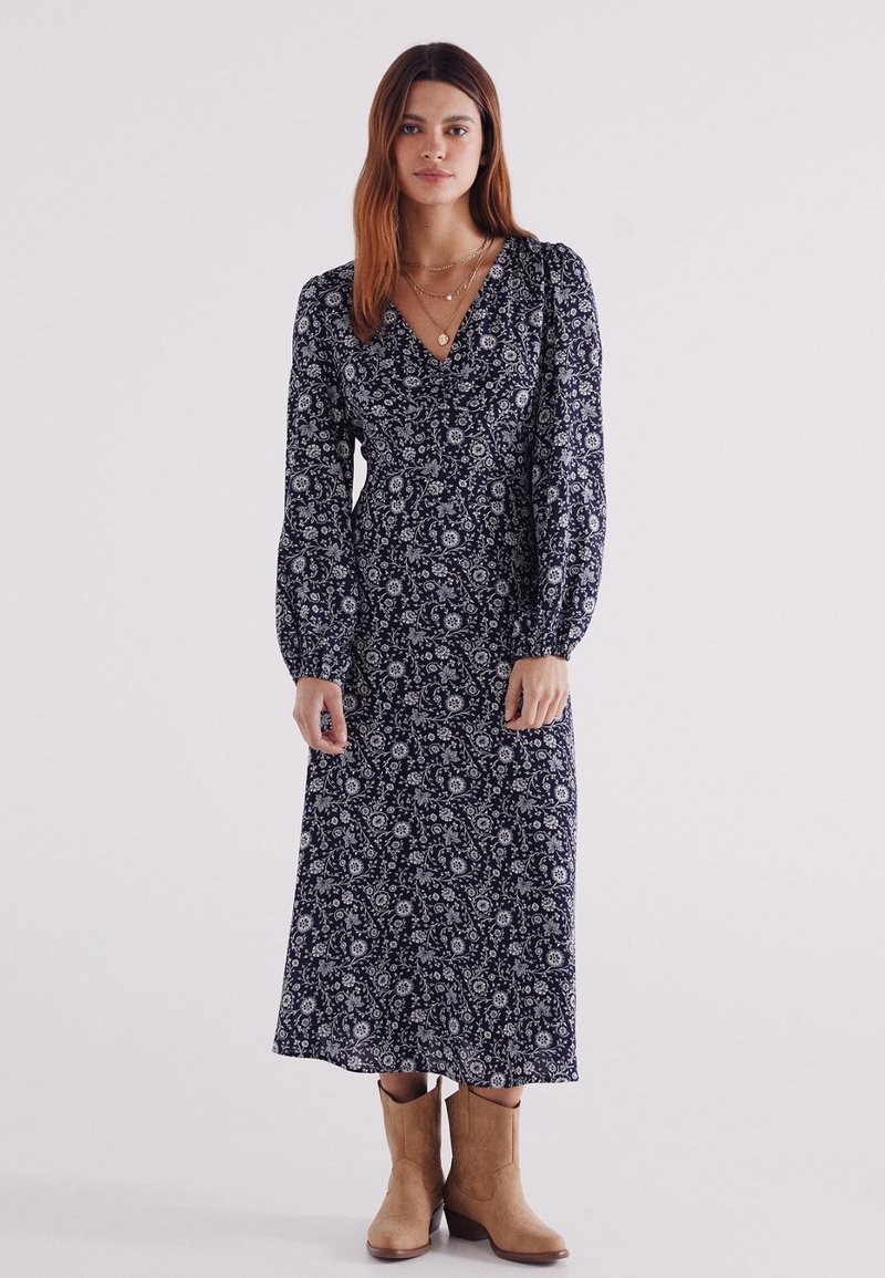 Marineblaues Maxikleid mit langen Puffärmeln, V-Ausschnitt und tailliertem Schnitt, aus leichtem Stoff mit dezenten Druckdetails.