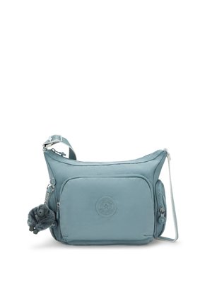 Borsa a tracolla azzurro chiaro realizzata in morbido tessuto, con una tasca frontale, un'etichetta rotonda con logo e un charm peloso attaccato alla cerniera.