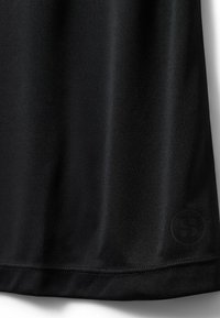 Čierna tkanina s hladkým povrchom a malým, decentným kruhovým logom blízko dolného okraja na pravej strane.