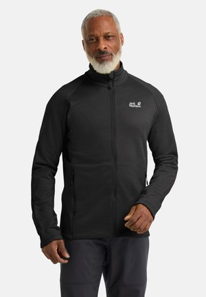 Zwarte ritsjack gemaakt van zachte materialen, met een hoge kraag, zijzakken en het "Jack Wolfskin"-logo op de linkerborst.