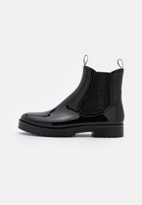 Bottes Chelsea en cuir verni noir avec des panneaux élastiques sur les côtés, des languettes de tirage, une semelle épaisse et un logo de la marque en relief sur le côté.
