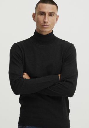 Suéter negro de cuello alto en un material de punto suave, con mangas largas y acentos acanalados en los puños y el dobladillo.