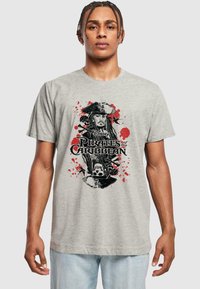 Gray cotton t-shirt featuring a black and red graphic print of a pirate, with splashes of red and "Pirates of the Caribbean" text.