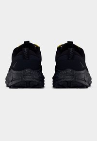 Mustad spordijalatsid tekstuuriga pealispinna, silmatorkava keskosa ja täpilise tallaga. Omavad kollast paelade süsteemi ja tõmbetutti.