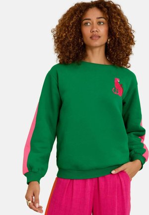 Felpa verde con strisce rosa sulle maniche, caratterizzata da una grafica rossa di leopardo sul petto. Realizzata in tessuto morbido con polsini a coste.