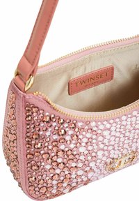 Borsa rosa con superficie strutturata decorata con paillettes, dettagli in oro e chiusura con cerniera. Interno foderato in tessuto beige, con etichetta del marchio.