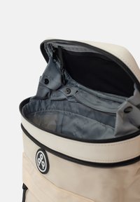 Sac à dos en PVC PE avec un extérieur crème, une doublure intérieure grise, une fermeture zippée sur le dessus et un cordon de serrage ajustable. Présente un logo circulaire à l'avant.