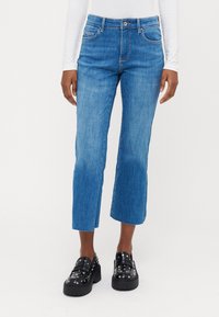 Modri-denim kavbojke s ravnim krojem, krajšo dolžino in rahlim zbledelostjo. Imajo zanke za pas, sprednje žepke in zadrgo.