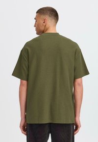 Olive green short-sleeve t-shirt featuring a textured pattern, crew neck design, and a relaxed fit, displayed from the back.