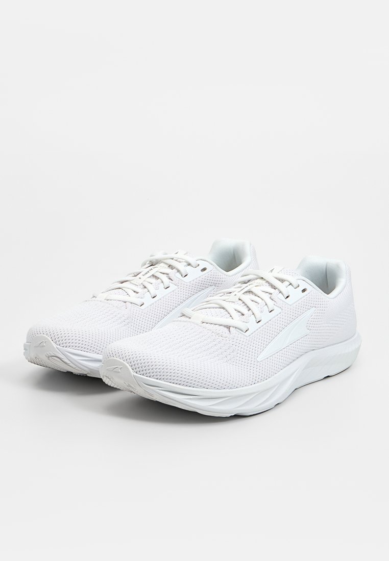 Zapatillas deportivas blancas con parte superior de malla, punta redonda, cordones finos y suela acolchada. Patrones texturizados notables en la superficie.