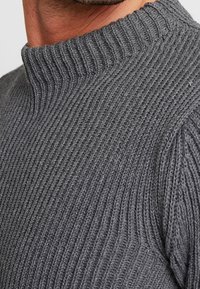 Grauer gestrickter Pullover mit einem hohen, gerippten Kragen. Verfügt über vertikale Rippstrukturen und ein tailliertes Design, hergestellt aus weichem, mittelschweren Material.