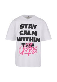 Balta kokvilnas T-krekls ar īsām piedurknēm, uz kura redzams uzraksts treknā melnā krāsā "STAY CALM WITHIN THE CHAPS" un rozā grafitija stila akcenti.