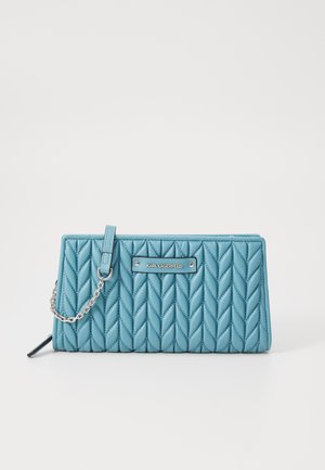 Quilted blue handbag with a chain strap and metal logo plate. Features herringbone pattern and smooth texture, with a structured silhouette.
