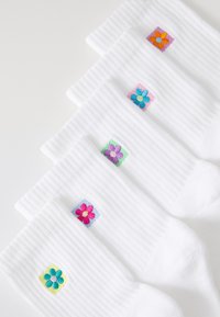 Socks in white ribbed material, featuring embroidered flower designs in various colors on square patches. Five pairs displayed.