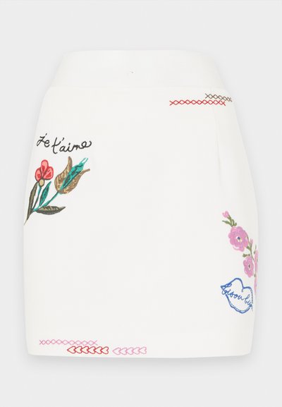 White skirt featuring colorful floral embroidery in pink, red, and green. Includes decorative stitching details on the hem and phrase "Je t'aime."