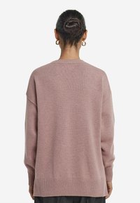 Rosa oversized Pullover mit strukturierter Oberfläche. Verfügt über gerippte Bündchen und Saum, überschnittene Schultern und einen Rundhalsausschnitt.