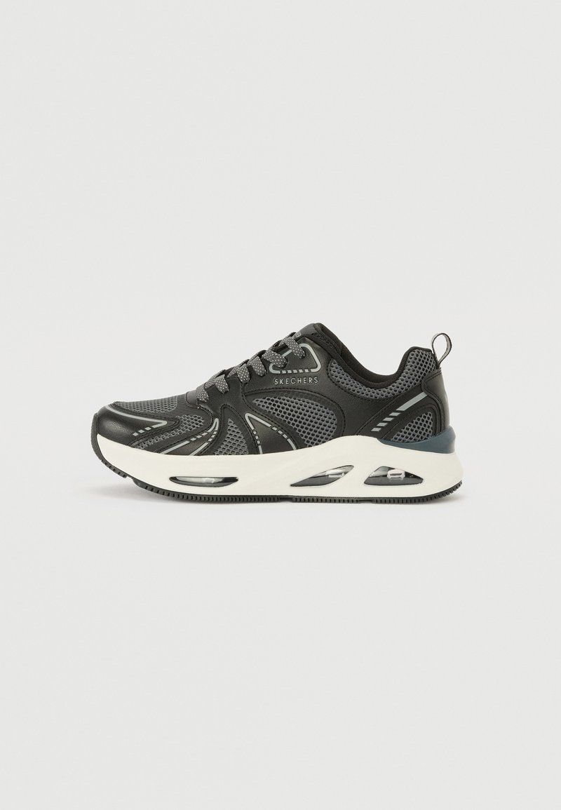 Shoe atlético preto com parte superior em malha e acentos sintéticos. Apresenta uma sola branca com bolso de ar visível e sola de borracha texturizada.