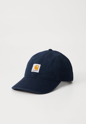 Navy blue cotton baseball cap with curved brim, featuring a white square patch with a yellow logo on the front and six ventilation eyelets.