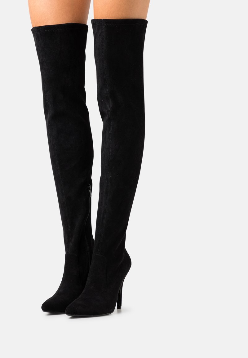 Bottes hautes au-dessus du genou en daim noir avec un bout pointu et un talon stiletto haut. Dotées d'une fermeture éclair latérale pour un enfilage facile. Texture lisse.
