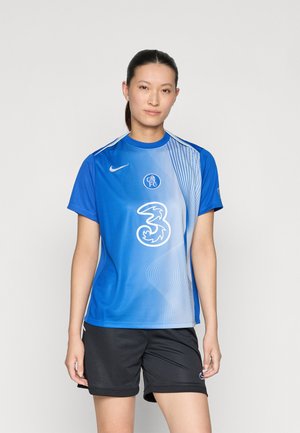 Tricou de fotbal Nike albastru cu un design în gradient, având un logo circular și un grafic „3”. Combinat cu pantaloni scurți sport negri.