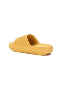 Chanclas amarillas de goma texturizada, con una tira ancha y una suela plana y acolchada con detalles acanalados para un mejor agarre.