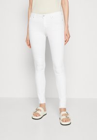 Jeans blancos ajustados, hechos de una tela de algodón elástico con una textura suave, que presentan un diseño clásico de cinco bolsillos y cierre de botón metálico.