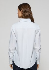 Vit randig skjorta med bakre yoke, långa ärmar, knappade manschetter och rundad nederkant. Slät tyg med en ren design.