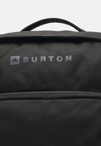Sac à dos noir avec une finition texturée, arborant un grand logo gris "BURTON" et une poche zippée à l'avant.