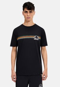 T-shirt nera a maniche corte con una striscia orizzontale colorata e il logo "ellesse" sul petto. Materiale in cotone morbido.