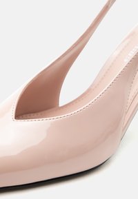 Γυαλιστερό γόνατο με χοντρό τακούνι, ανοιχτή πίσω με λουράκι, σε ανοιχτό ροζ χρώμα, με μυτερή μύτη και χαμηλά κομμένες πλευρές.