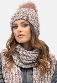 Knit hat in pink and white with a fluffy pom-pom; paired with a matching textured scarf, showcasing a cozy, chunky knit design.