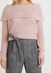 Maglione rosa lavorato a maglia con design scaldadino e motivo a maglia testurizzato, abbinato a pantaloni a quadri a vita alta con cintura annodata.