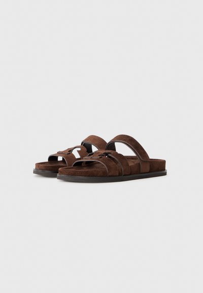 Brown suede slide sandals with two straps and textured footbed, featuring a subtle design accent detail and sturdy sole.